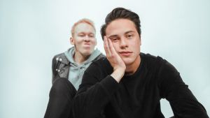 Yhdessä kavereiden kanssa soittaminen on helpottanut musiikkialan vähemmän hohdokkaiden käänteiden käsittelemisessä. Kuumaa-yhtyeen Jonttu Luhtavaara ilveilee etualalla istuvalle Johannes Brotherukselle, joka nojaa päätään tylsistyneen näköisenä kämmeneensä. Miehet istuvat valkoisen taustan edessä.