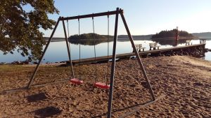 Arkivbild. Simstranden vid Vitteludden i Houtskär. Pargas stad ansökte om att få använda danaarvet från en avliden Houtskärsbo till utvecklandet av Bläsnäs simstrand i Pargas. Däremot uppmärksammades exempelvis inte simstranden vid Vitteludden i Houtskär. Tom strand och tomma gungor på Vitteludden i Houtskär.