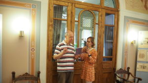Björn Dahla och Ruth Illman på Donnerska institutet man och kvinna står och tittar i bok framför en stor gammal glasdörr