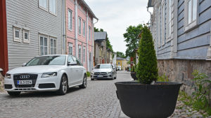 Såhär ser de nya krukorna på Kyrkogatan ut. Kullerstensgata i Borgå med livlig trafik.