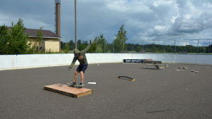 Skejtramperna inne i rinken är gjorda av trä och är inte lika hållbara som i en ordentligt byggd skejtpark. En pojke som åker på en skejtboard inne i en rink.