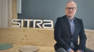 Markus Terho är projektledare för Hållbar vardag. Man sitter och ler bredvid en skylt där det står SITRA