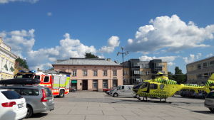 Läkarhelikoptern landade mitt på torget som fungerar som parkering under andra dagar än torgdagar. En brandbil och en räddningshelikopter står parkerade på ett torg.