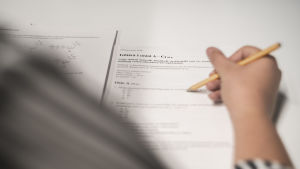 Det hade varit svårt att ordna inträdesförhör på distans, enligt universiteten. En kvinna skriver ett inträdesprov. Man ser inte kvinnans ansikte.
