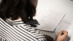 Ungefär 15 procent av högstadieeleverna får ingen vidare utbildning efter grundskolan. En kvinna skriver ett inträdesprov. Man ser inte kvinnans ansikte.