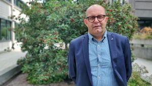 Christer Holmlund, förbundsordförande på Finlands Svenska Lärarförbund. Person i blå kpostym står framför ett träd