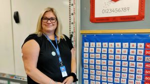 Pamela Leka, speciallärare har märkt av att semesterpenningen har minskat. En person står framför en whiteboard och bredvid en plansch med alfabetet. och en kalender.