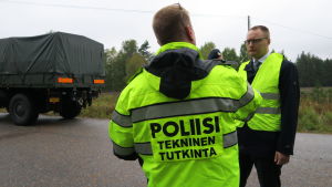 Äldre kriminalkonstapel Ivo Tatarinov och försvarsadvokat Mikko Puhakka var med och synade olycksplatsen under rättegångsdag 1. En polis och en advokat i gula kläder diskuterar i närheten av en plankorsning.