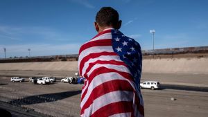 En centralamerikansk migrant insvept i USA:s flagga ser ut över Tijuana-flodens så gott som torra flodbädd på den mexikanska sidan om en gränsövergång mot USA. Bilden är tagen 25.11.2018. En centralamerikansk migrant insvept i USA:s flagga ser ut över Tijuana-flodens så gott som torra flodbädd på den mexikanska sidan om en gränsövergång mot USA. Bilden är tagen 25.11.2018.