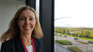 Sjöfartsdirektör Ulla Lainio på Business Finland tror på Finlands chanser när Ryssland bygger nytt. Sjöfartsdirektör ulla Lainio på Business Finland leende framför ett fönster.