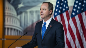 Den demokratiska kongressledamoten Adam Schiff ledde riksrättsprocessen mot Trump för ett år sedan. En politiker talar till journalister. Två flaggor i bakgrunden.