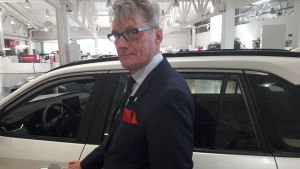 Mikko Huopalainen är vd för Toyota Tsusho Nordic Oy. Vd Mikko Huopalainen poserar framför en bil i en bilaffär.