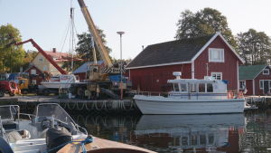Martins båthall har varit verksam i Rosala i nästan 40 år. Båthamn i Rosala med båtar i förgrunden och en lyftkran på stranden