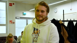 Elis Höckerstedt har erfaranheter av att både studera innan ekonomerna flyttade till ASA-huset och nu efteråt. Han säger att det fanns mycket större lokaler att röra sig i då, men att de helt enkelt fått nöja sig med mindre rum nu. en ung man i vit tröja bland andra studenter
