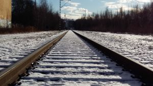 Ett tomt järnvägsspår en solig vinterdag med snö.