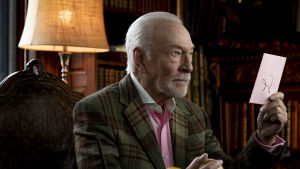 Vad står det i det ljusröda brevet? Harlan Thrombey (Christopher Plummer) visste ett och annat om sin familj. Harlan Thrombey (Christopher Plummer) sitter vid sitt skrivbord och ser allvarlig ut samtidigt som han håller ett ljusrött kuvert i sin hand.