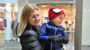 Petra Vähämaa tittar i skyltfönster med sonen. Petra Vähämaa håller sin son i famnen och tittar på någonting.