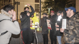 Omkring 20-30 unga män deltar i demonstrationen mot Migris deportationer till Irak. Unga män ropar och demonstrerar ute. De har plakat, med texten "Rätt till liv".