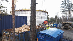 Här reser sig Kyrkslätts nya vattentorn. Ett vattentorn intäckt i vitt plast. I framgrunden ser man en man som jobbar med att bygga tornet.
