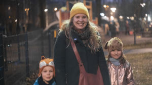 Anna Saarnisto är glad över att Elvira och Edvin fått plats på svenskspråkigt dagis. En kvinna står utanför en lekpark med ett barn i var hand. Hon ser glad ut.