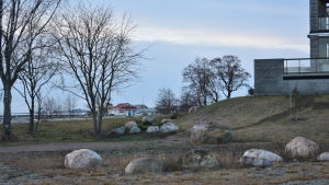 Många vill promenera på udden. En gräsplan och stenar vid ett vitt flervåningshus.