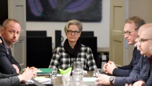Riksförlikningsmannen Vuokko Piekkala vid förhandlingsbordet tillsammans med Skogsindustrins arbetsmarknadsdirektör Jyrki Hollmén (till vänster) och Pappersförbundets ordförande Petri Vanhala (till höger). Kvinna sitter i mitten av ett bord. Kvinnan är riksförlikningsmannen Vuokko Piekkala. Bredvid henne Petri Vanhala och Jyrki Hollmén.