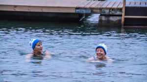Tävlingar i vinterbad fungerar som vilken simtävling som helst. Här tar Arja Palmu och Marianne Kanerva ett dopp. Två glada kvinnor med mössa på huvudet simmar