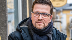 Klaus Härö har funderat mycket på hur olika människor relaterar till sorg. Klaus Härö sitter på en bänk och tittar ut ur bilden
