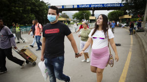 Enderson Ramirez och Natahlie Ramirez jobbar i Cúcuta men bor kvar i Venezuela. ” Vi känner oss inte trygga med de allmänna sjukhusen i Venezuela. Man måste köpa och ta med sig all materiel själv i samband med förlossningen - sprutor, kompressorer och bedövning vid kejsarsnitt” säger Natahlie Ramirez. Ett par går hand i hand på gatan. Han har munskydd och hon är gravid i rosa kjol.