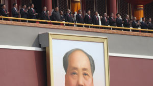Kinas beskådar en militärparad vid Tiananmen i Peking under folkrepublikens 70-årsjubileum i oktober 2019. President Xi Jinping, sjätte från vänster, är iklädd traditionell Mao-kostym. Kinesiska ledare följer med en militärparad vid Tiananmen (Himmelska fridens port) i Peking under Folkrepublikens 70-årsjubileum i oktober 2019. Ledarna är fotograferade ovanför det enorma Mao-porträttet vid porten.