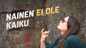 Teoskuvassa Salla Hämäläinen näyttää räppitunnusta sormillaan muinaisten kalliomaalausten edessä