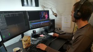 Stefan arbetar direkt mot en dator i Stockholm. En man sitter framför tre datorskärmar och redigerar video.