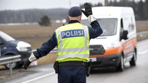 Under perioden 28.3-15.4.2020 var Nyland isolerat från resten av landet. En polis fotograferad bakifrån står och dirigerar trafik vid en väg.