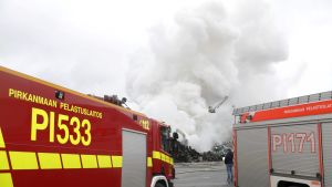 Tio enheter från räddningsverket i Birkaland deltar i släckningsrabetet. Ett enormt rökmoln bakom ett par brandbilar.