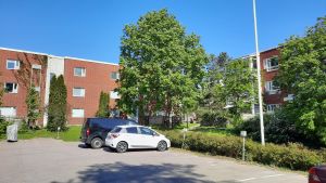 Bostadsområdet består av flera trevåningshus i röd tegel. Parkeringsplats och våningshus i röd tegel.