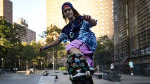 Nina Moran spelar Kirt. En ung tjej är fotad nedifrån när hon åker skateboard och håller just på att göra ett trick. I bakgrunden syns gröna träd och höghus.