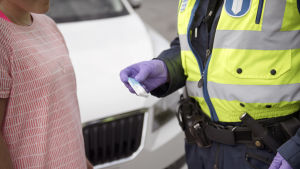 Narkotikabrotten har ökat. Person i t-skjorta och en polis som har håller ett drogtest i handen.