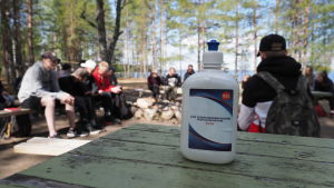 Hygienen är i fokus när lägergårdarna öppnar. Koronakevään rippileiriläiset istuskelevat ringissä, etualalla käsidesipullo