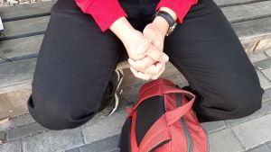 Beslutet att flytta ut var svårt att fatta. Händer i kors, ryggsäck på marken.