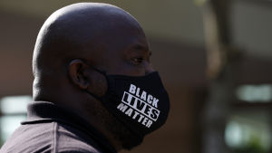 En åskådare utanför kyrkan bar Black Lives Matter-mask. BLM-rörelsen har protesterat mot polisvåldet mot svarta runtom i USA och även i andra länder. En man bär en skyddsmask med texten Black lives matter.