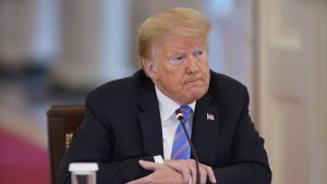Trump ställer in partikonvent på grund av coronaviruset. En äldre kostymklädd man med ljust hår sittande vid ett skrivbord. President Donald Trump i Vita huset den 26 juni 2020.