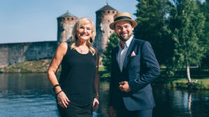 Karita Mattilan konsertti avaa Festariheinäkuun. Karita Mattila ja Ville Matvejeff seisovat hymyilen Olavinlinnan edustalla.