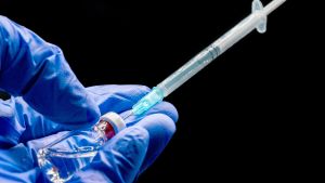 Vaccin mot coronaviruset utvecklas genom hundratals projekt omkring i världen.Illustrationsbild. Närbild av en hand som håller i vaccin.