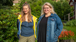 Nora Garusi och Minna Parkkonen broderar korsstygn med kaxigt budskap. Nora Garusi och Minna Parkkonen poserar i trädgården. De håller båda på med korsstygnsbroderi med feministiskt tema.