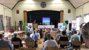 Ordförandedebatten i föreningshuset i Ypäjä lockade ett sjuttiotal åhörare. Alla Centerns tjugo distrikt kommer att arrangera egna debatter före partikongressen i september. Tre av Centerns ordförandekandidater på en liten scen och åhörare i salen.