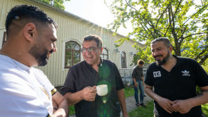 Konvertiterna Anis Zidan Al-sudani och Samer Al-Khazraji lär sig om kristendomen och Bibeln med pastor Ramez Ansara. Det finns endast några kvinnor i gruppen eftersom de flesta flyktingar år 2015 var män. Kvinnorna deltar hellre i familjeaktiviteter av kulturella skäl. I den arabiska kulturen är det inte en accepterad norm att kvinnor vistas i grupper med män, säger Ansara. Ansara Ramez, seurakuntapastori, Perkkaan kappelin pihalla kahvilla.