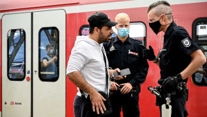 Munskydd är obligatoriska bland annat i tåg, men nu kan en utvidgning av åtgärderna bli aktuell. Poliser stoppar en person i Köln som brutit mot coronareglerna.