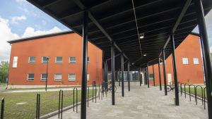 Fångar som anses kunna anpassa sig till friare förhållanden förs till de öppna fängelserna i Finland. Här är en bild från Jyväskyläs nya öppna fängelse. en vy över jyväskylä öppna fängelse, en orange stenbyggnad med en promenadgång med tak och cykelställningar framför
