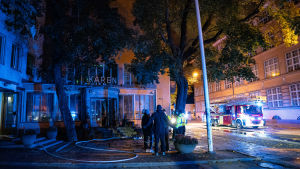 En brand utbröt i en av matsalarna på Kåren den 17 oktober. Personer står utanför Kåren i Åbo. I bakgrunden en brandbil.
