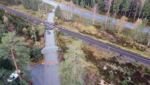 Enligt hovrättens dom finns det inga bevis på att annat handlande skulle ha förhindrat olyckan. Plankorsningen i Skogby där det skedde en olycka i oktober 2017 mellan rälsbuss och militärfordon. Bilden visar platsen från luften med järnväg, grushögar och staket som stänger av korsningen.